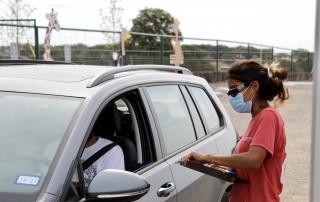 Employee talking to guest in their car.